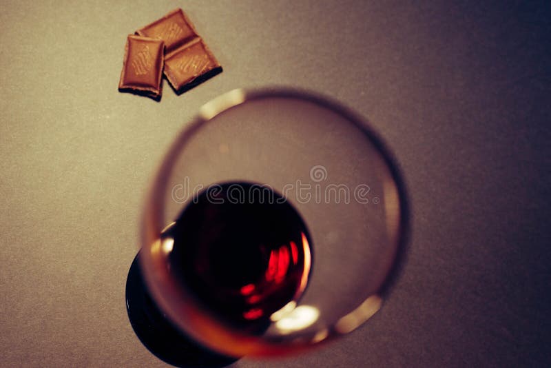 Un vetro delle fette del cioccolato e del vino rosso fotografia stock Un vetro delle fette del cioccolato e del vino rosso fotografia stock