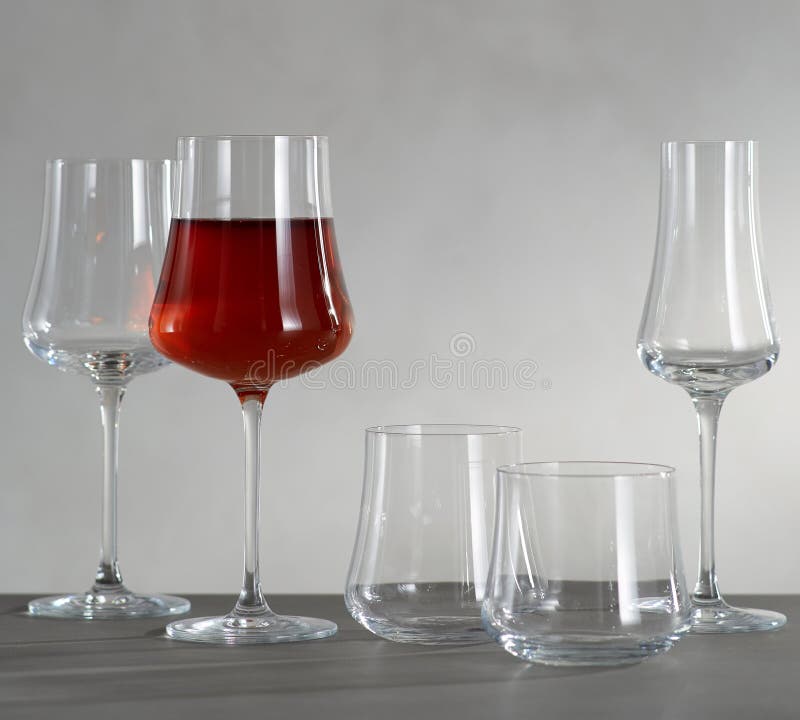 Un vetro di vino rosso e di quattro vetri di vino vuoti immagini stock Un vetro di vino rosso e di quattro vetri di vino vuoti immagini stock