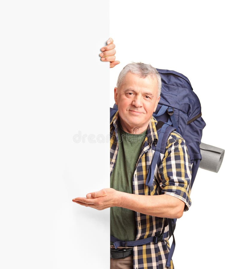 Un viaggiatore con zaino e sacco a pelo maturo che gesturing su un comitato bianco immagine stock
