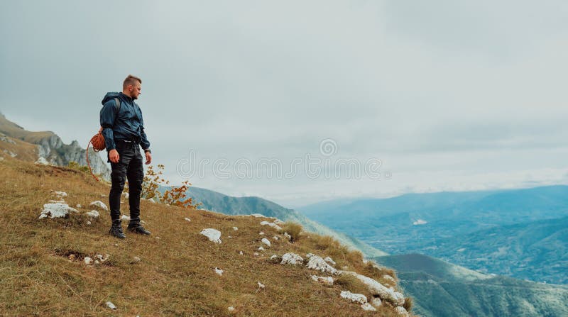 Un viaggiatore maschio in piedi sulla cima della montagna durante il viaggio di avventura. immagine stock libera da diritti