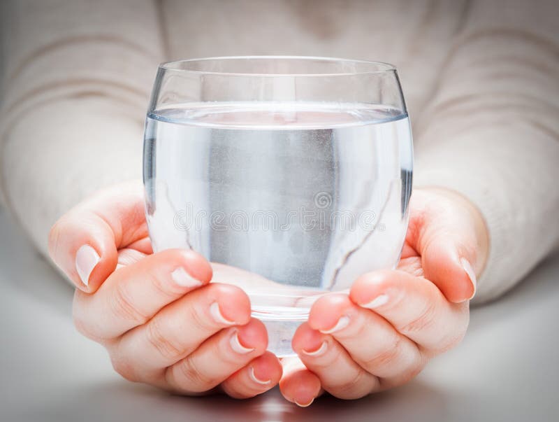 Un vidrio de agua mineral limpia en las manos de la mujer Protección del medio ambiente, bebida sana imágenes de archivo libres de regalías