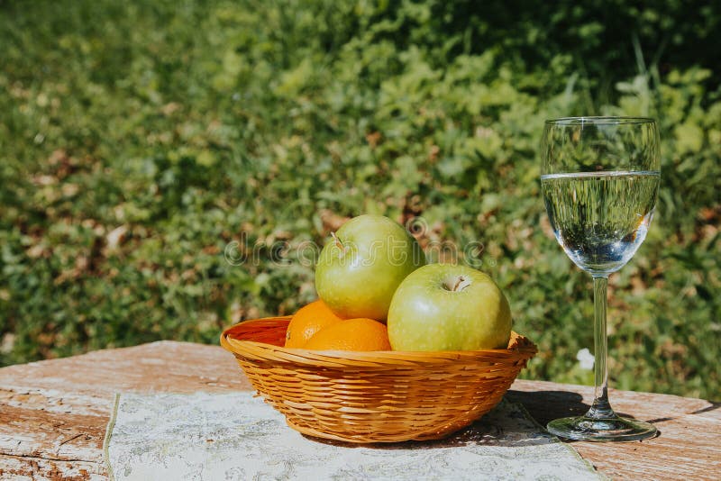 Un vidrio de agua y de las manzanas frescas de Apple en una cesta en una tabla de madera fotografía de archivo libre de regalías Un vidrio de agua y de las manzanas frescas de Apple en una cesta en una tabla de madera fotografía de archivo libre de regalías