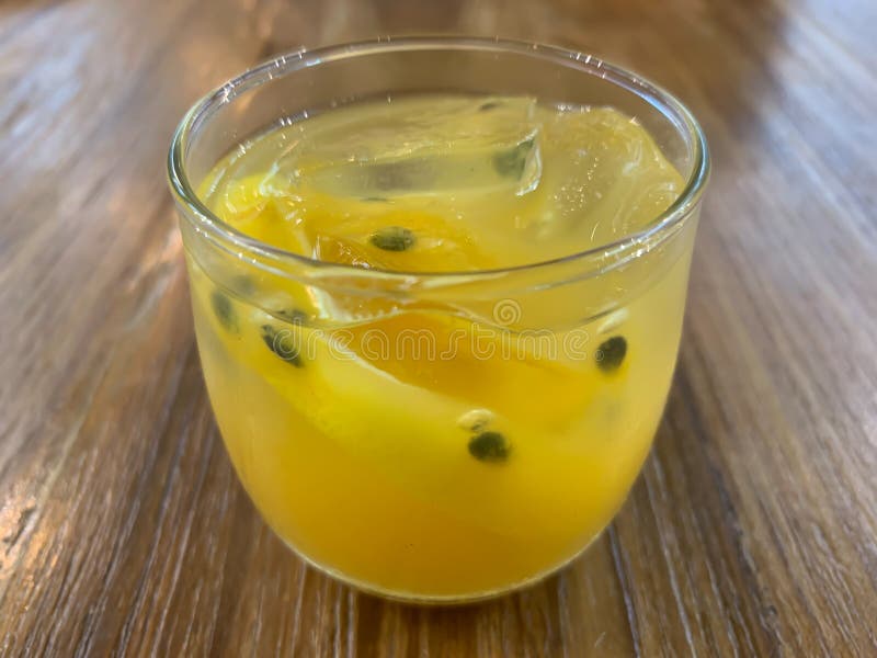 Un vidrio de fondo del jugo de la fruta de la pasión imagen de archivo Un vidrio de fondo del jugo de la fruta de la pasión imagen de archivo