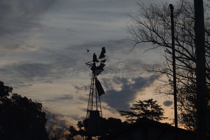 Un viejo molino de viento al atardecer imagenes de archivo