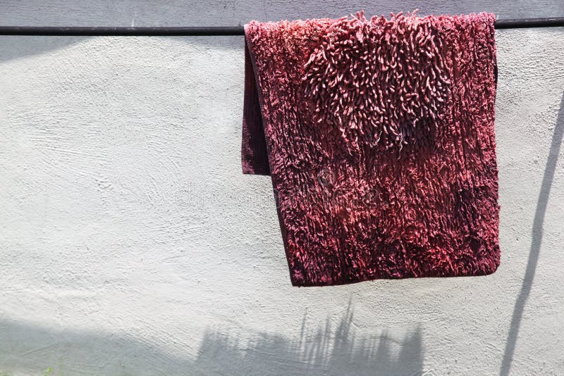Un vieux tapis dans lavé rose et de séchage au soleil photos stock Un vieux tapis dans lavé rose et de séchage au soleil photos stock