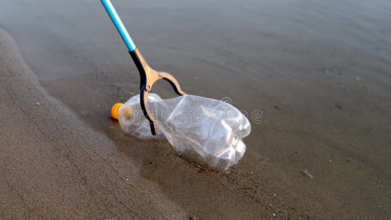 Un volontaire supprime les déchets en plastique d'une rivière ou d'un lac à l'aide d'un gros plan d'un outil de jardin. Pollution photo libre de droits