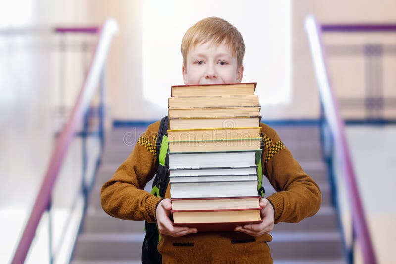 Un écolier va en bas avec des livres dans des ses mains photo libre de droits Un écolier va en bas avec des livres dans des ses mains photo libre de droits