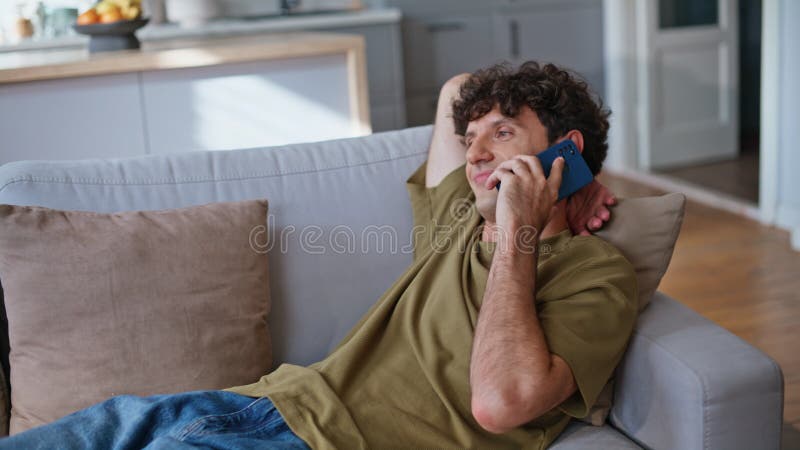 Un étudiant paresseux bavarder cellulaire sur le canapé à la maison le week-end se sentir détendu closeup photographie stock libre de droits