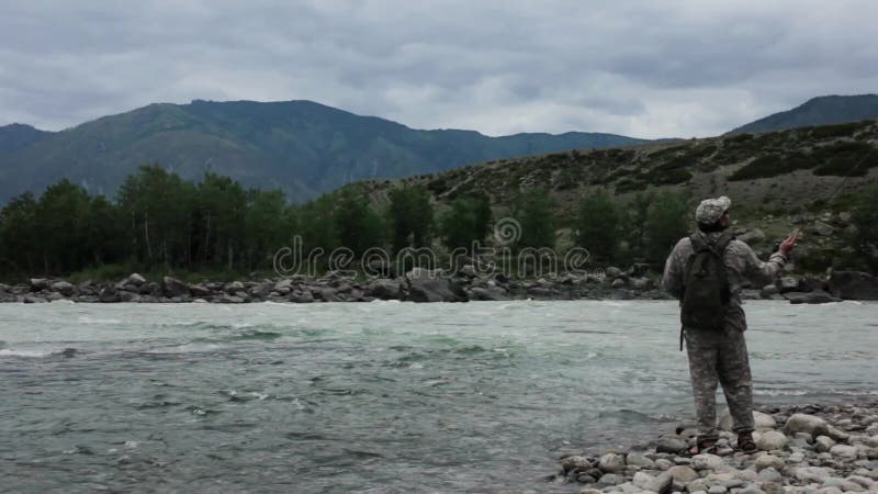 Un Ãºnico pescador en un rÃ­o tormentoso estÃ¡ pescando en un dÃ­a soleado de verano