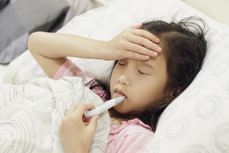 Una bambina asiatica a letto malata fotografie stock libere da diritti Una bambina asiatica a letto malata fotografie stock libere da diritti
