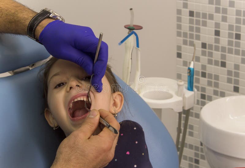 Una bambina che si siede in una sedia dentaria ad un ufficio dentario fotografia stock libera da diritti Una bambina che si siede in una sedia dentaria ad un ufficio dentario fotografia stock libera da diritti