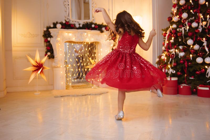 Una bambina graziosa con capelli biondi che indossano il Natale rosso e frizzante si veste immagini stock Una bambina graziosa con capelli biondi che indossano il Natale rosso e frizzante si veste immagini stock