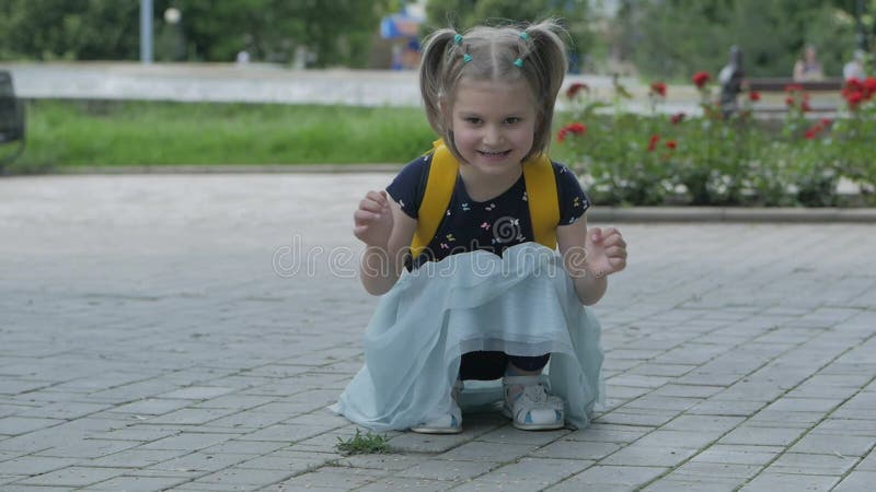 Una bambina nel parco nutre dei piccioni di grano.
