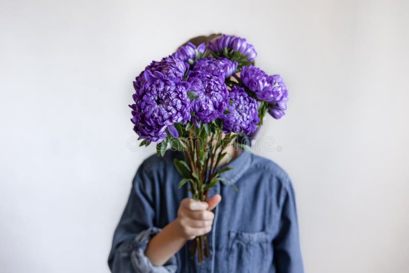 Una bambina tiene in mano un bouquet di crisantemi blu fotografie stock