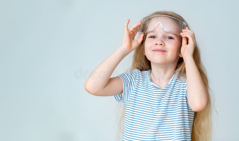 Small girl removes safety goggles from dust for experiments. Small girl removes safety goggles from dust for experiments