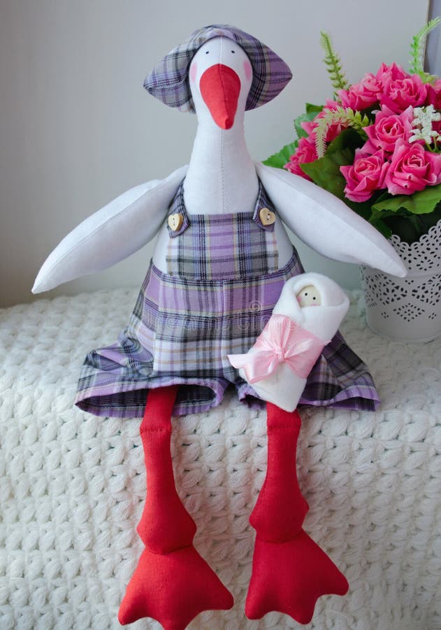 Doll stork in a checkered hat with a newborn baby. Scandinavian style of design ( tildas dolls). Doll stork in a checkered hat with a newborn baby. Scandinavian style of design ( tildas dolls)