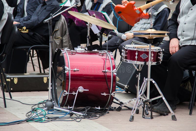 Una banda che prepara eseguire nella via ad estate all'aperto Insieme marrone rossiccio del tamburo, chitarra rossa, mic, l'altra immagine stock libera da diritti Una banda che prepara eseguire nella via ad estate all'aperto Insieme marrone rossiccio del tamburo, chitarra rossa, mic, l'altra immagine stock libera da diritti