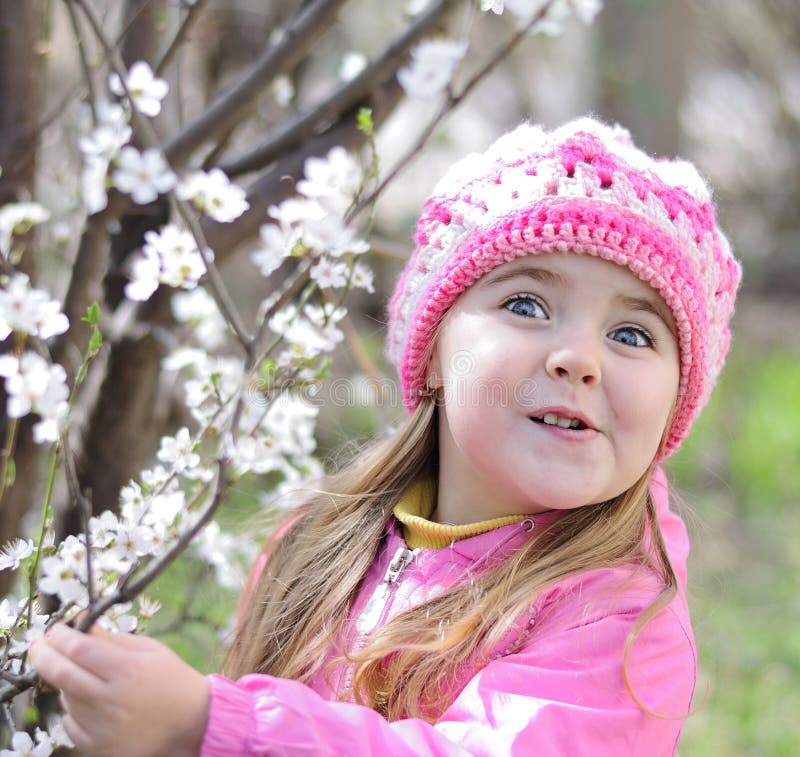 Una bella bambina vicino ad un albero di fioritura fotografie stock libere da diritti Una bella bambina vicino ad un albero di fioritura fotografie stock libere da diritti