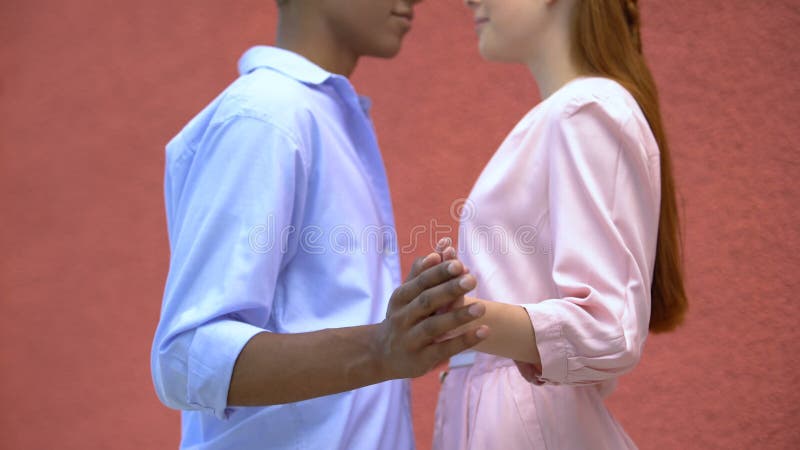 Una bella coppia di adolescenti che si stringe la mano l'una accanto all'altra, primo appuntamento stock footage