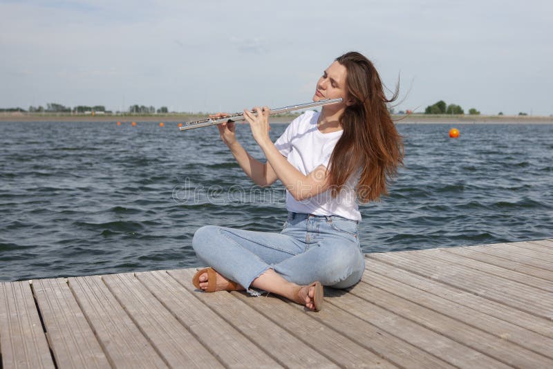 Una bella donna che posa in spiaggia mentre giocando su una flauto fotografia stock libera da diritti Una bella donna che posa in spiaggia mentre giocando su una flauto fotografia stock libera da diritti