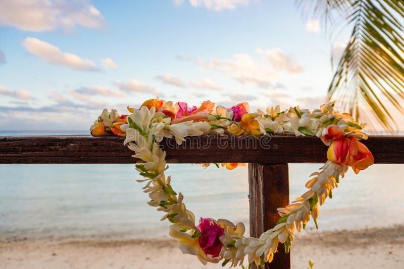 A beautiful lei of flowers rests on a the railing of a wooden deck overlooking a lagoon in French Polynesia in the South Pacific; copy space. A beautiful lei of flowers rests on a the railing of a wooden deck overlooking a lagoon in French Polynesia in the South Pacific; copy space