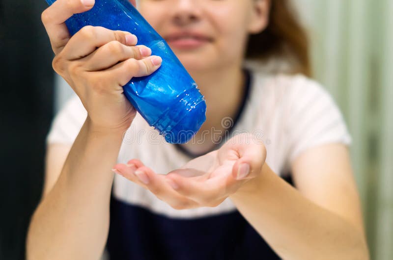 Una botella de plástico con una cinta adhesiva para niños en la mano de una mujer. la mano de una adolescente vierte el lima azul de un frasco transparente en la palma de su mano. concepto de entretenimiento de juegos.