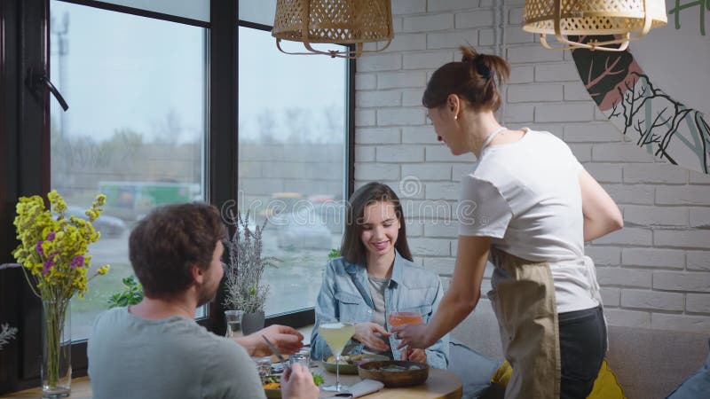 Una cameriera amichevole in un caffè accogliente ha portato da bere a una coppia piacevole. un uomo e una donna sono venuti a pran archivi video