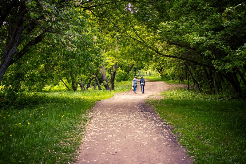 Una camminata di due giovani donne all'aperto in parco scenico a tempo di molla immagini stock libere da diritti Una camminata di due giovani donne all'aperto in parco scenico a tempo di molla immagini stock libere da diritti