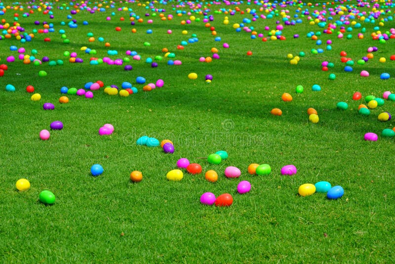 Una caza del huevo de Pascua con los huevos plásticos en un césped verde