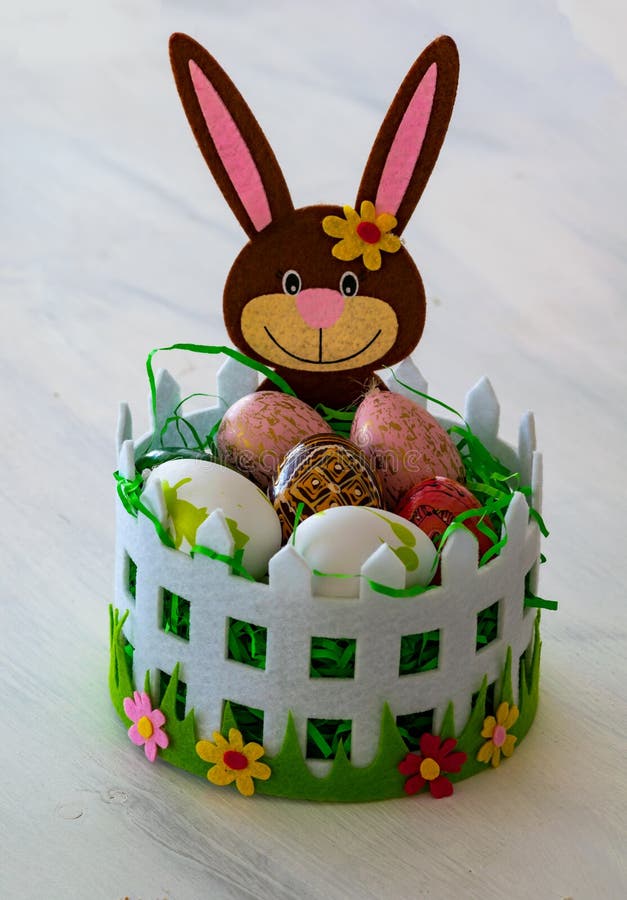 Una cesta cariñosamente adornada de Pascua con un conejito de pascua y huevos de Pascua coloridos fotografía de archivo libre de regalías Una cesta cariñosamente adornada de Pascua con un conejito de pascua y huevos de Pascua coloridos fotografía de archivo libre de regalías