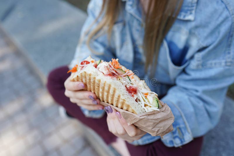 Una chica come shawarma en la calle. Comida rápida imagenes de archivo Una chica come shawarma en la calle. Comida rápida imagenes de archivo