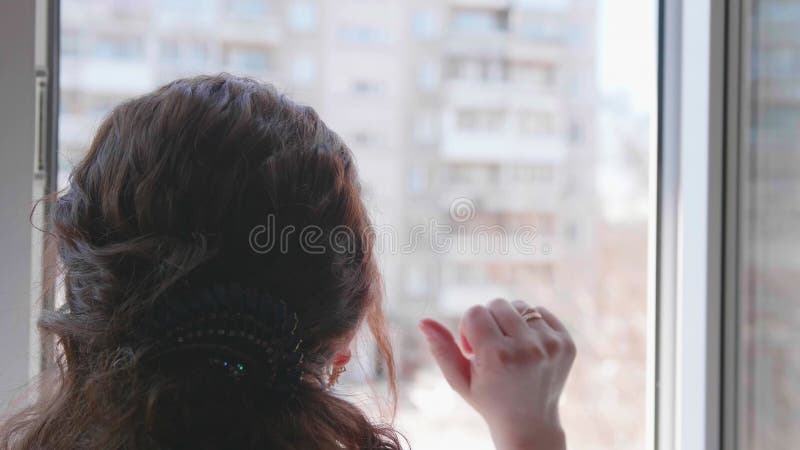 Una chica con una máscara protectora está sentada en casa con selfisolación. la niña se comunica a través de una ventana abierta c