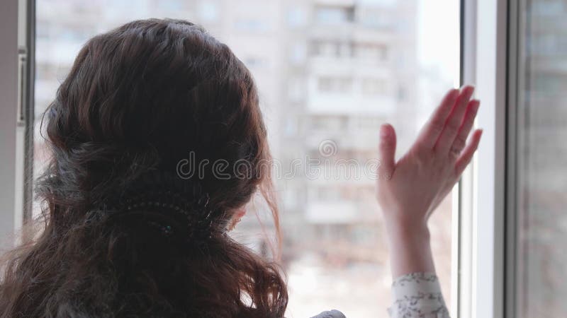 Una chica con una máscara protectora está sentada en casa con selfisolación. la niña se comunica a través de una ventana abierta c