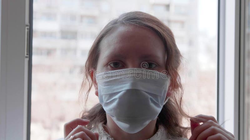 Una chica con una máscara protectora se sienta cerca de una ventana del hospital. prevención y protección de la salud y la segurid