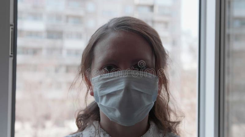 Una chica con una máscara protectora se sienta cerca de una ventana del hospital. prevención y protección de la salud y la segurid