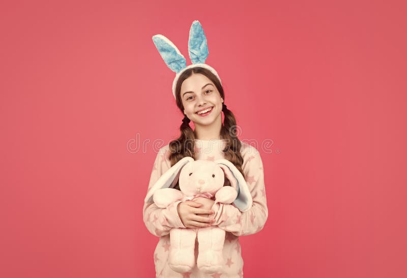 Una chica feliz de Pascua en orejas de conejo y pijamas jugando con una pascua feliz imágenes de archivo libres de regalías