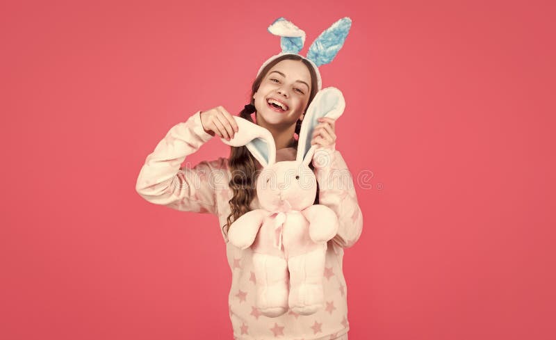 Una chica feliz de Pascua en orejas de conejo y pijamas jugando con una pascua feliz imagenes de archivo