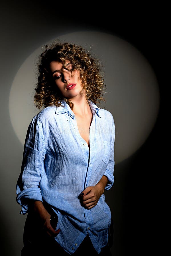Una chica hermosa es iluminada por un haz de luces teatrales foto de archivo Una chica hermosa es iluminada por un haz de luces teatrales foto de archivo