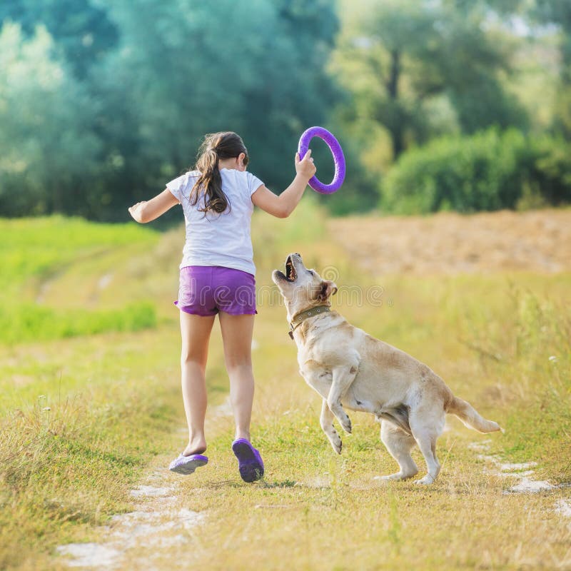Una chica joven con un perro corre a lo largo de una carretera nacional imagen de archivo Una chica joven con un perro corre a lo largo de una carretera nacional imagen de archivo