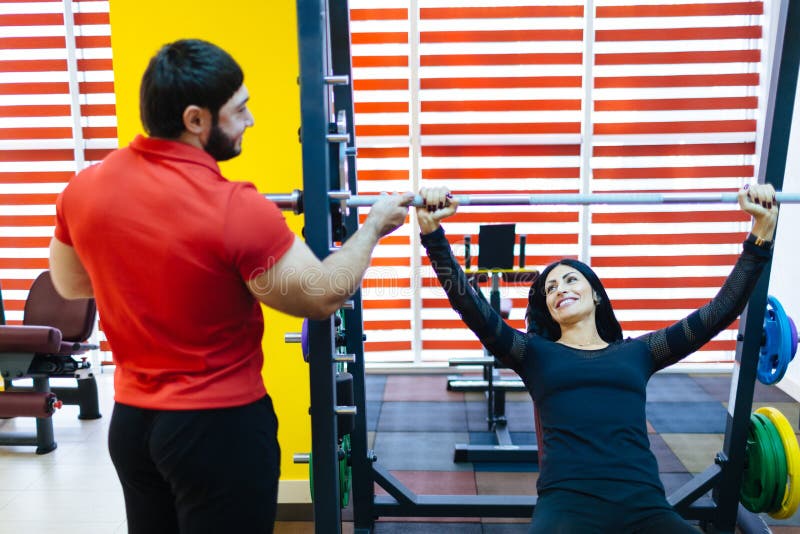 Una chica joven en el gimnasio que hace con un instructor personal foto de archivo libre de regalías Una chica joven en el gimnasio que hace con un instructor personal foto de archivo libre de regalías