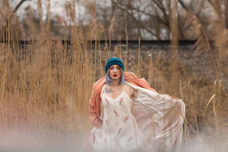 Una chica joven en un vestido blanco hermoso y un sombrero elegante presenta en un campo de trigo imágenes de archivo libres de regalías Una chica joven en un vestido blanco hermoso y un sombrero elegante presenta en un campo de trigo imágenes de archivo libres de regalías