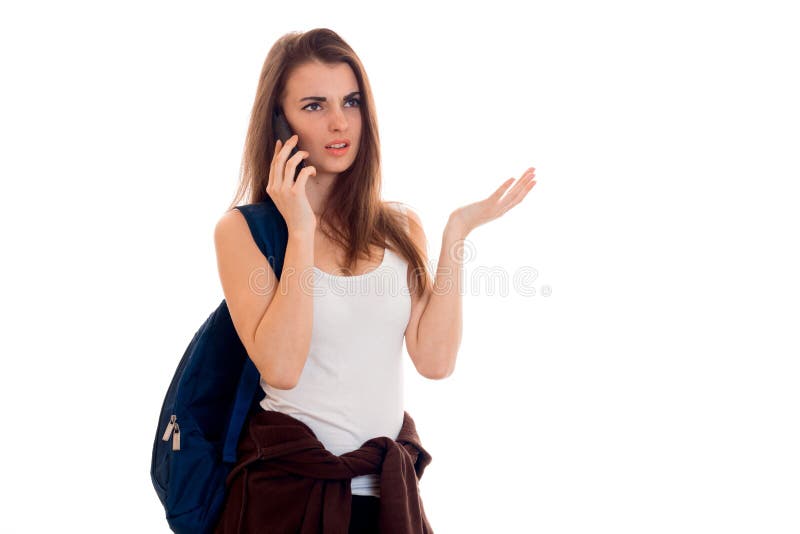 Una chica joven en una camiseta y con una mochila en el hombro con una persona seria que habla en el teléfono imágenes de archivo libres de regalías Una chica joven en una camiseta y con una mochila en el hombro con una persona seria que habla en el teléfono imágenes de archivo libres de regalías