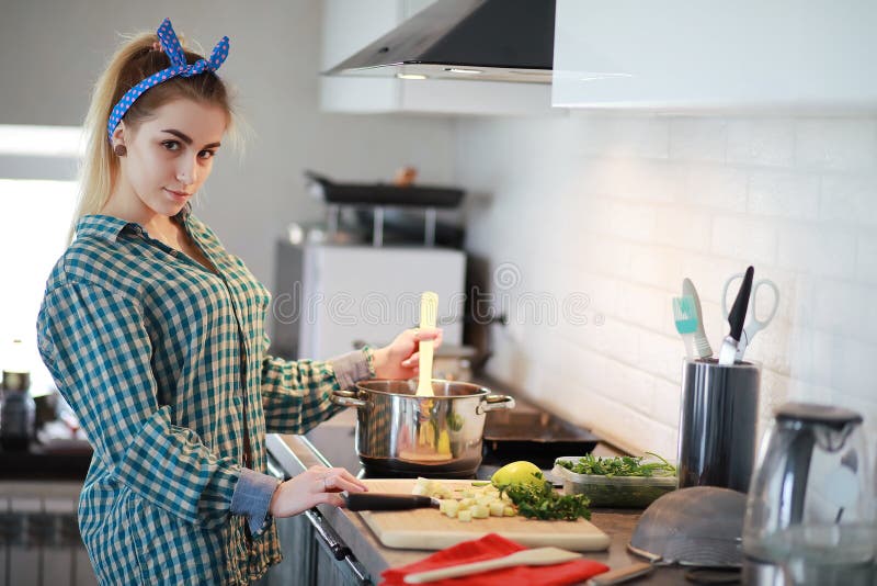 Una chica joven linda en la cocina prepara la comida imagen de archivo Una chica joven linda en la cocina prepara la comida imagen de archivo