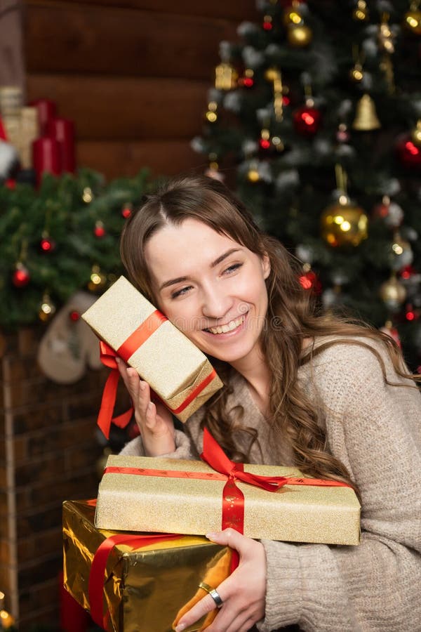 Una chica linda le presiona una caja de regalo a la cara y se ríe imagen de archivo libre de regalías