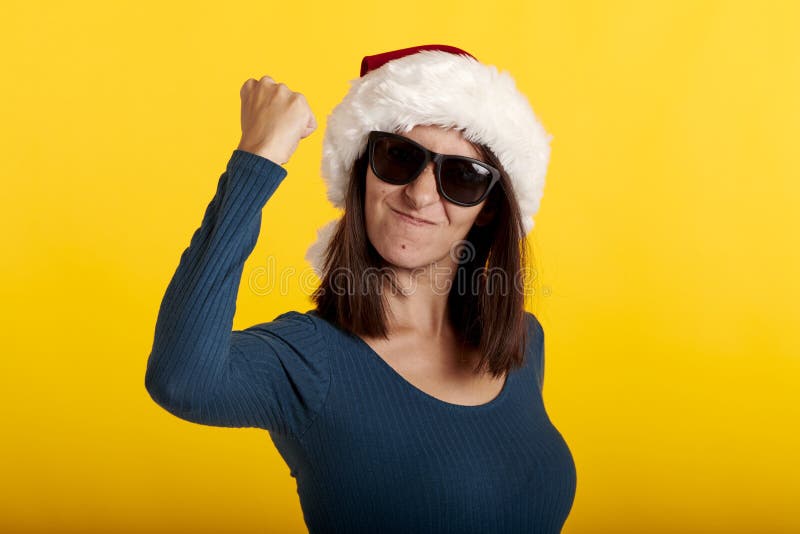 Una chica muscular con un sombrero de santa claus en un fondo amarillo imagen de archivo libre de regalías
