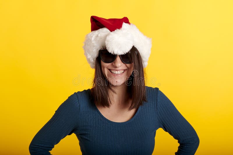 Una chica se hace un tonto en un sombrero de Papá Noel con un fondo amarillo fotografía de archivo libre de regalías