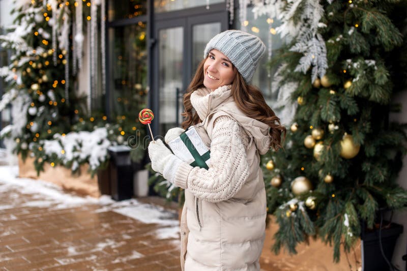 Una chica sonriente camina por la ciudad con un colorido chupete redondo y una caja de regalo fotos de archivo