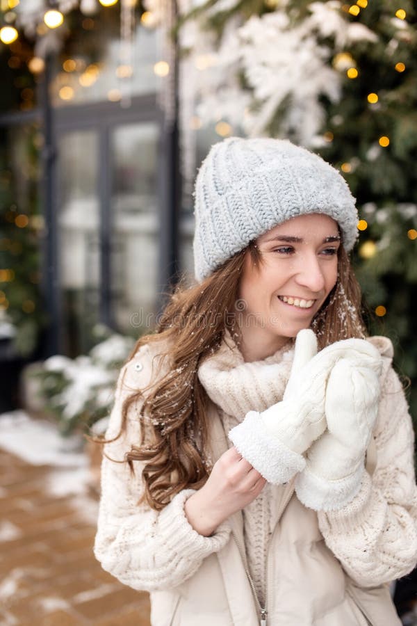 Una chica sonriente se saca los mitones para quitarle la nieve de la cara foto de archivo