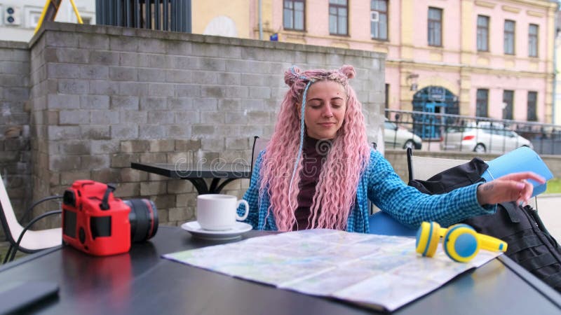 Una chica turista fuma sentada en un café callejero.