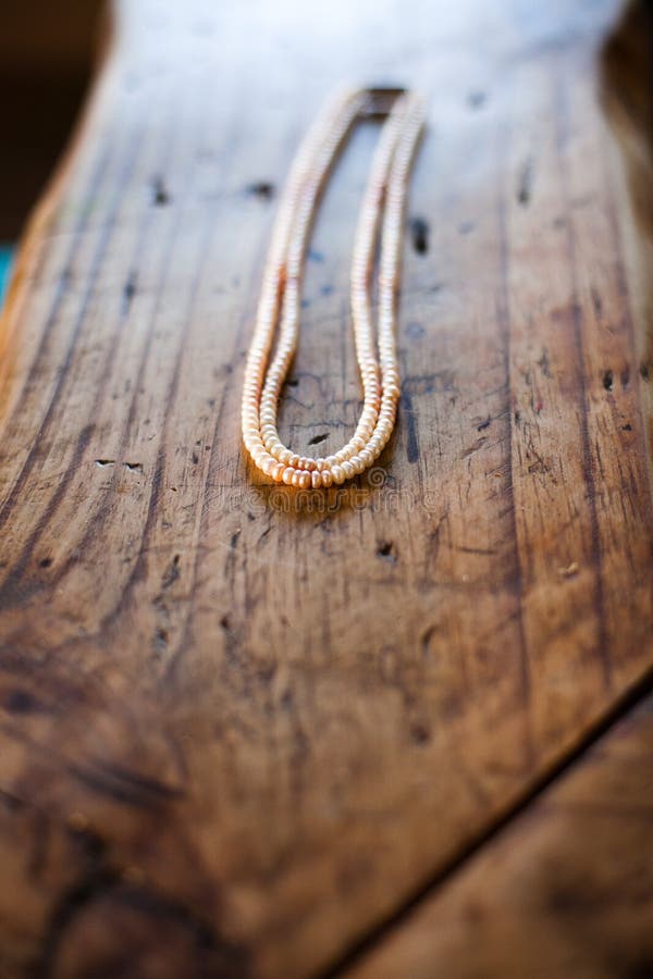 Una collana della perla di Hydrabad si siede su un banco di legno immagine stock libera da diritti Una collana della perla di Hydrabad si siede su un banco di legno immagine stock libera da diritti